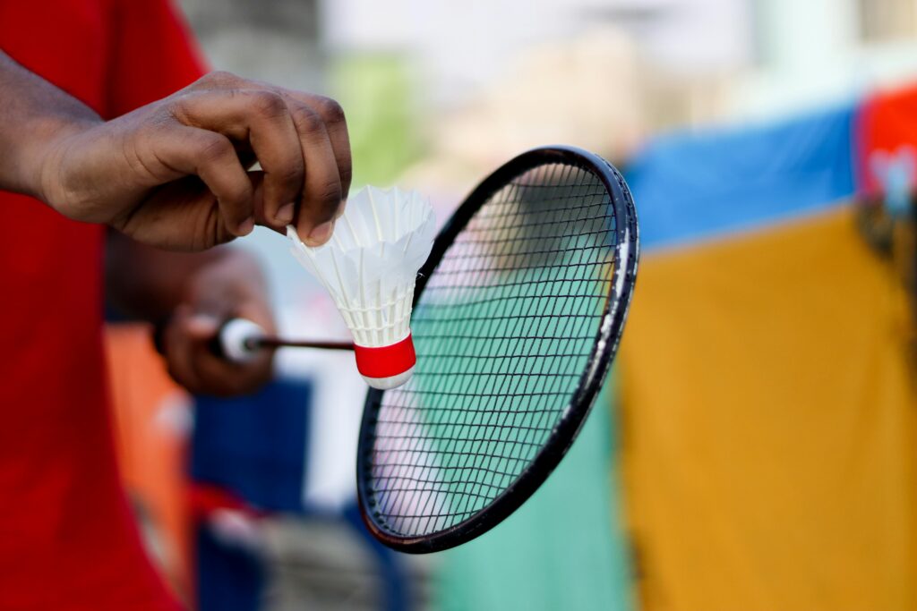 pexels photo 6878017 6878017 Close-up of a hand holding a shuttlecock and badminton racket, ready to serve.